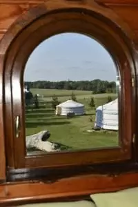 Les yourtes au travers de la fenêtre de la roulotte Finistère roulotte en bretagne : vue de la chambre